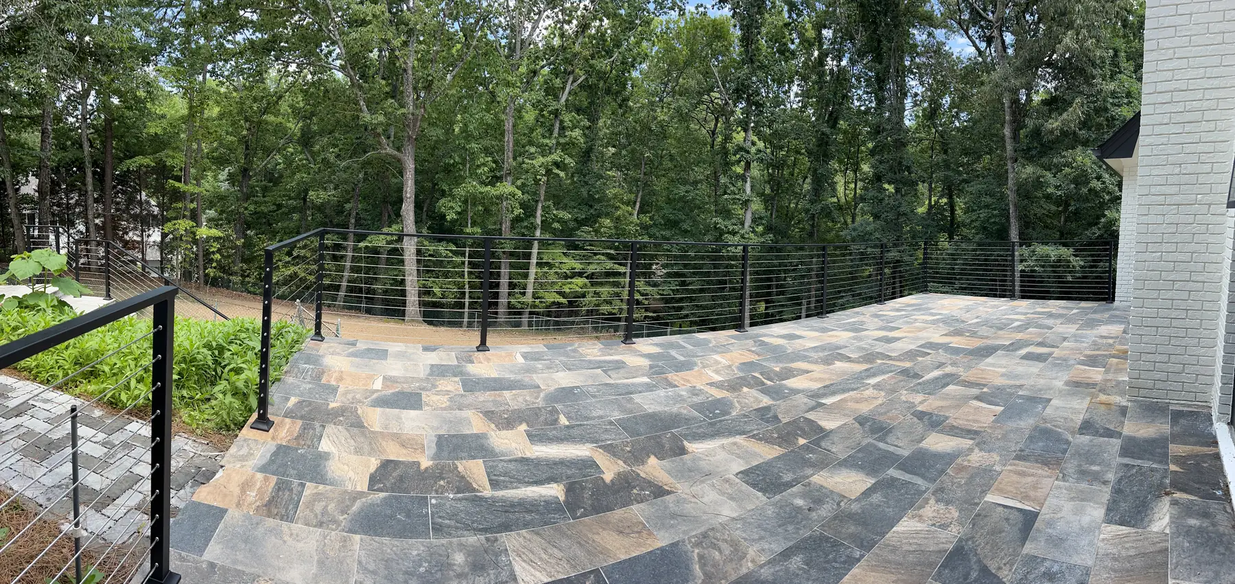 Steel cable railing built by Falcons Iron Design around a wide stone terrace