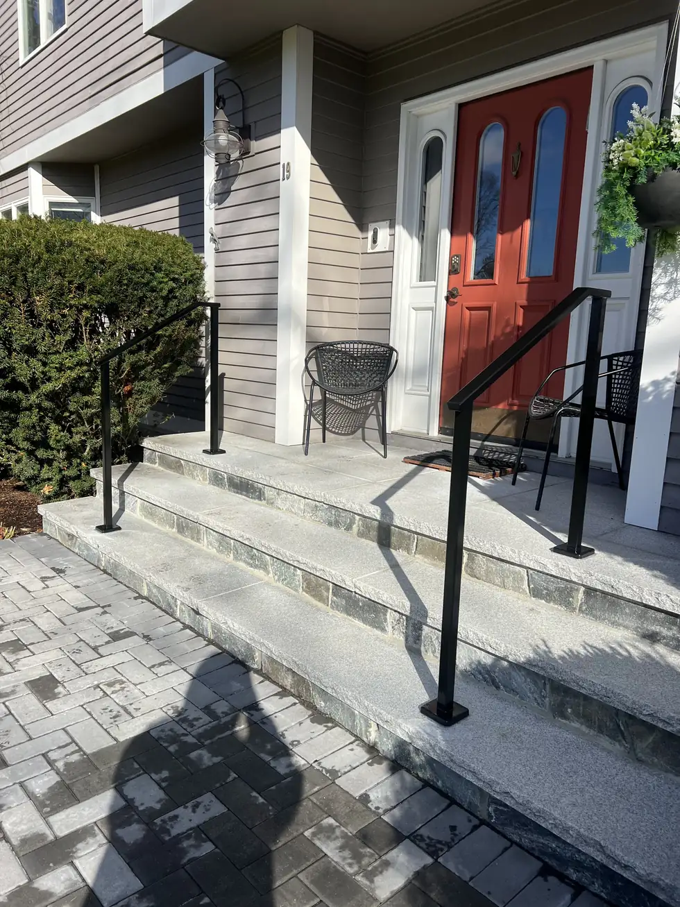 Black handrail on bluestone steps at a red door