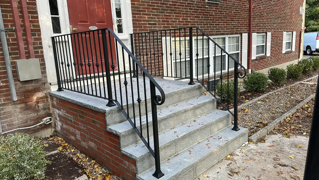 Black iron stair handrail on brick front steps