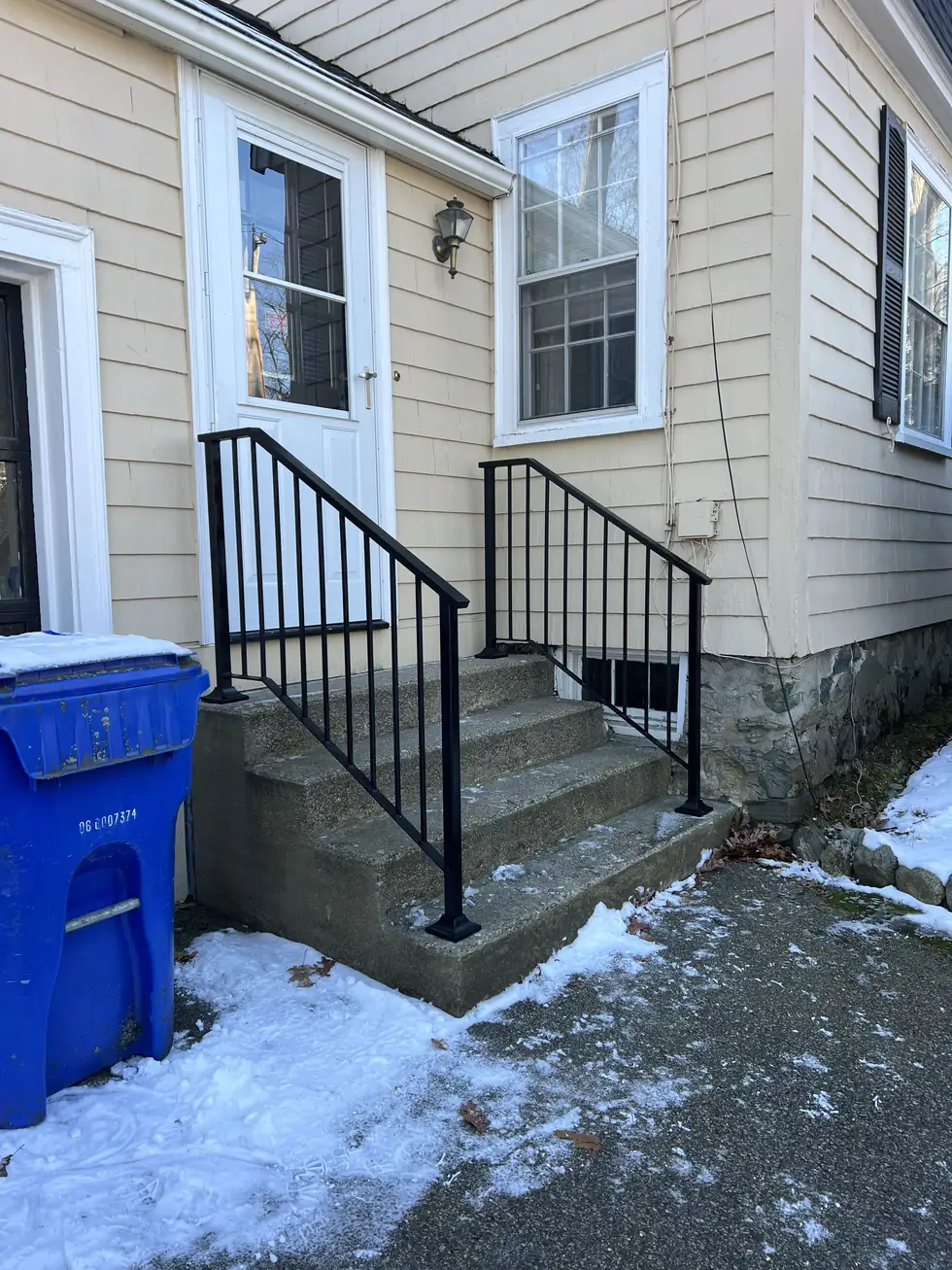 Black steel handrail on concrete side entry steps