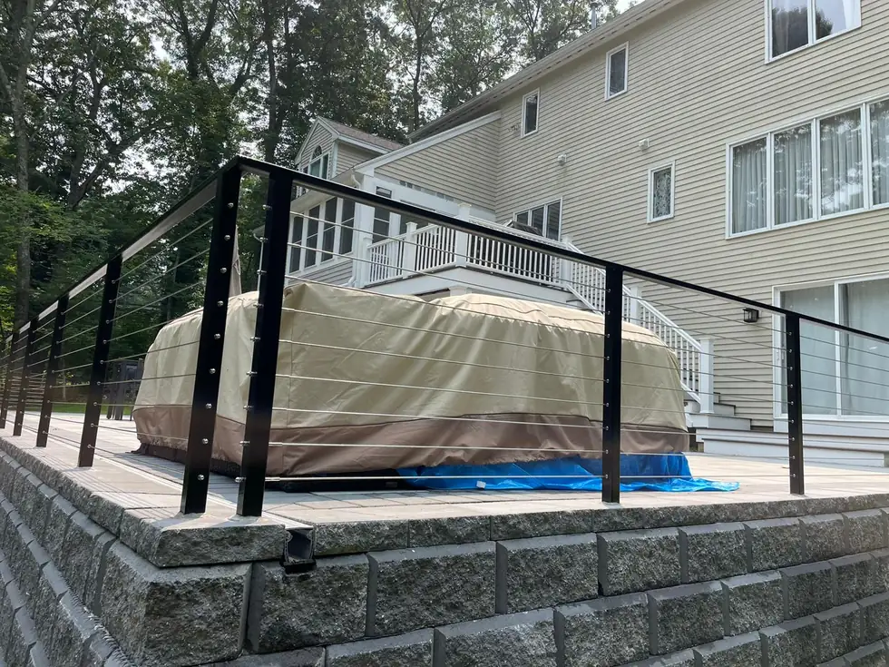 Cable railing on a block retaining wall beside a hot tub deck