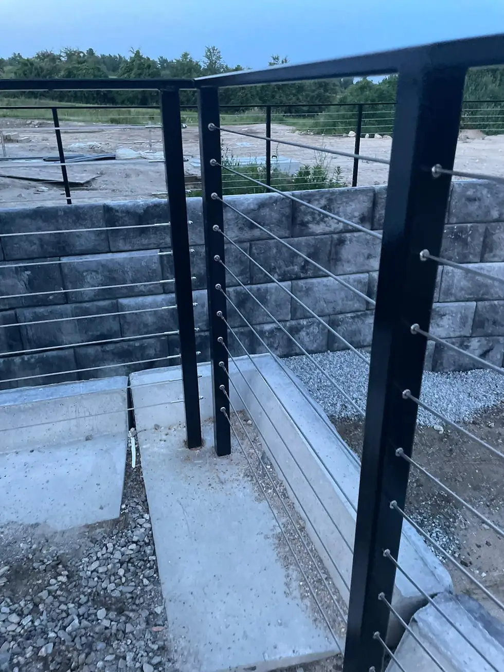 Cable railing corner post anchored to a concrete wall