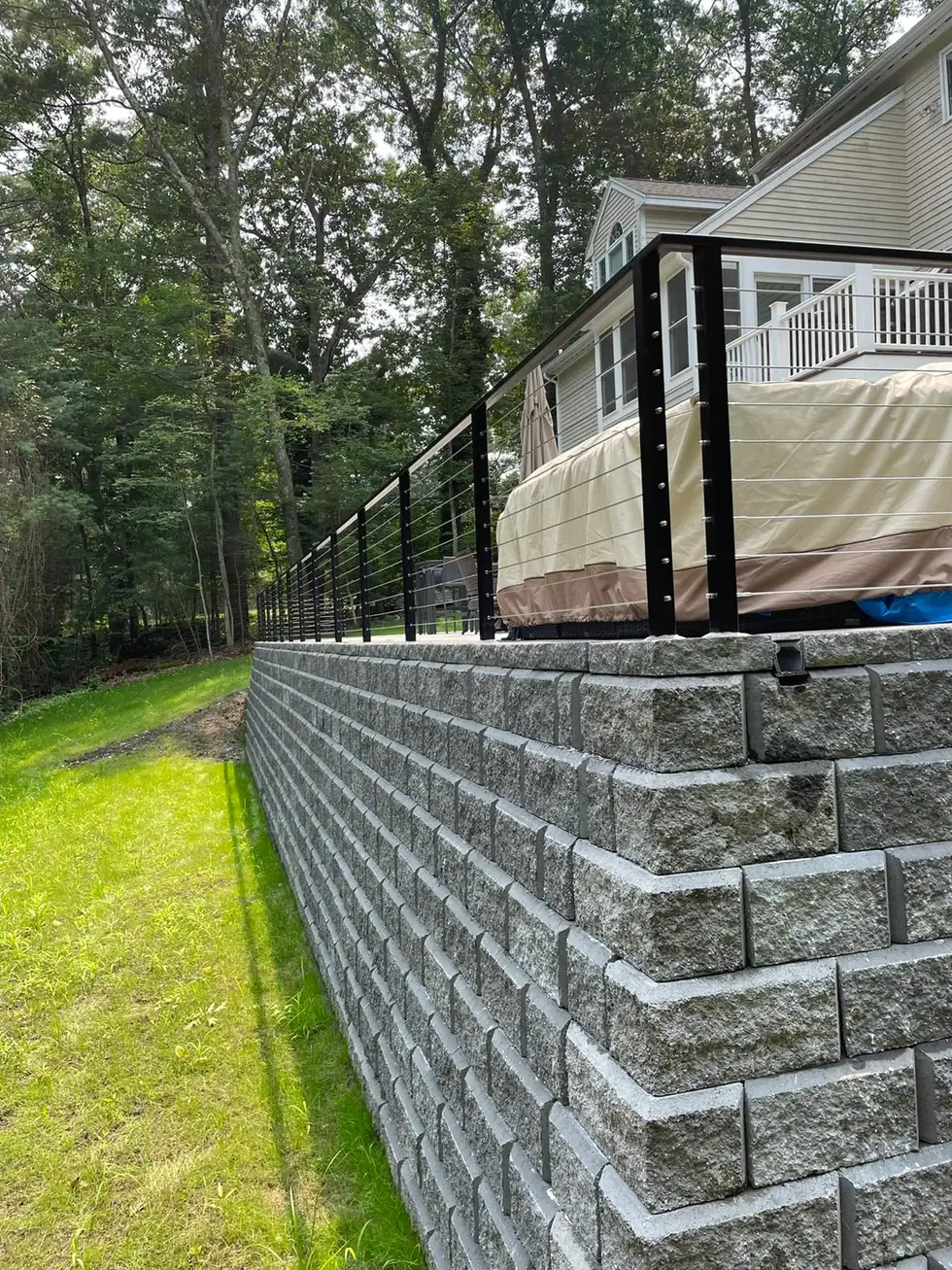 Cable railing along a granite block retaining wall above a lawn