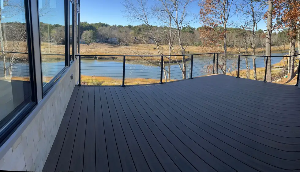 Black steel cable railing around a waterfront composite deck