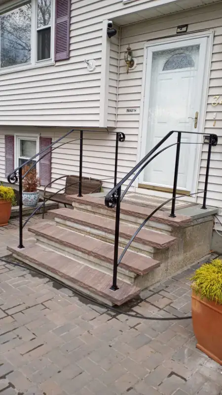 Curved scroll iron handrail on brick entry steps