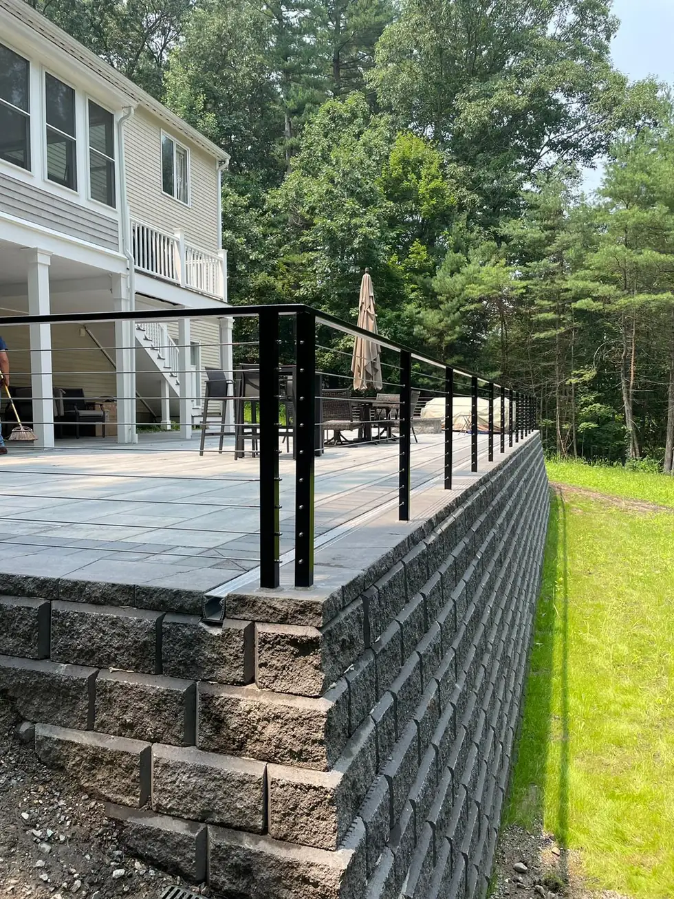 Backyard deck cable railing on a stone retaining wall