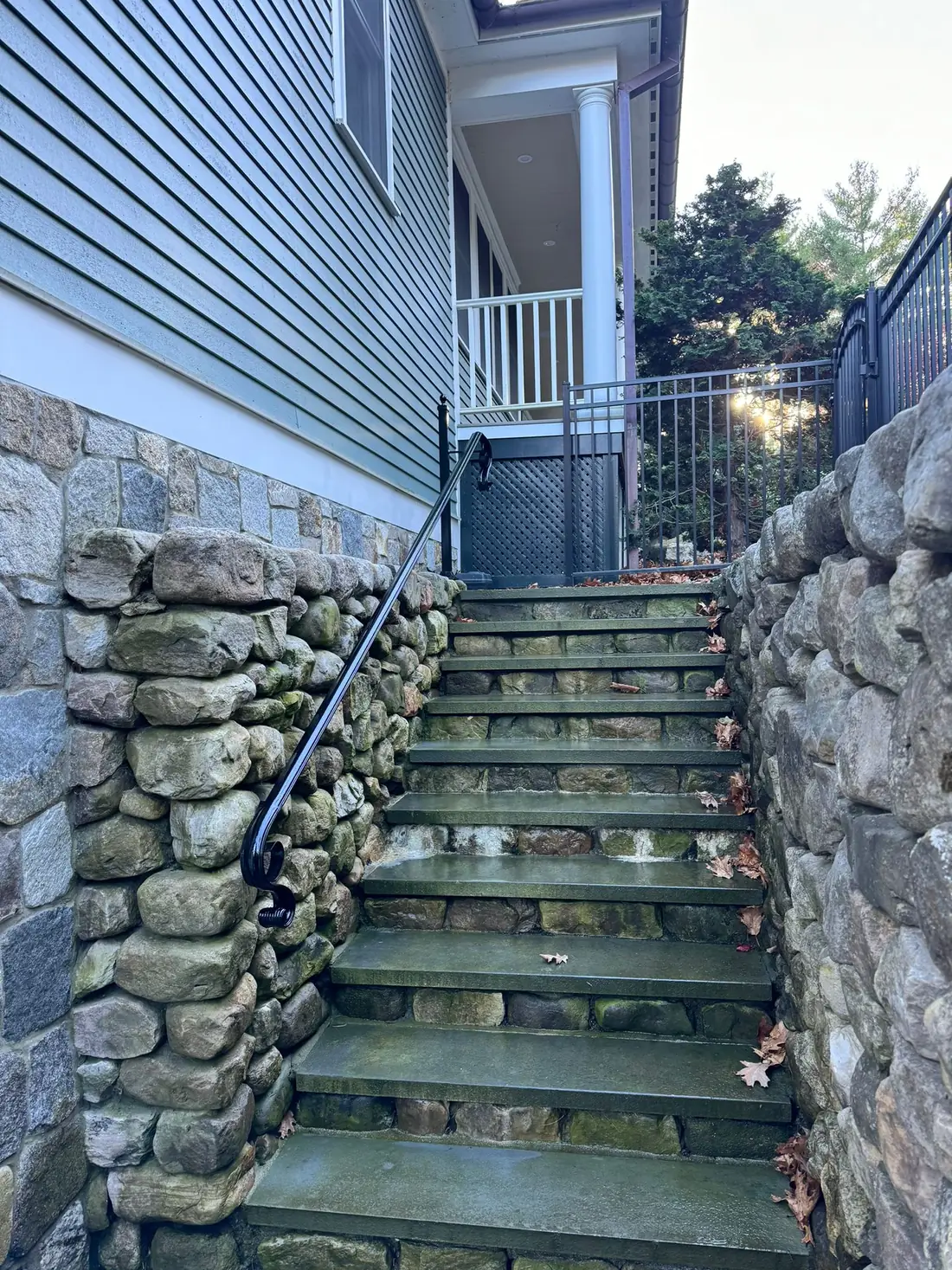 Granite step staircase with iron handrail and stone wall
