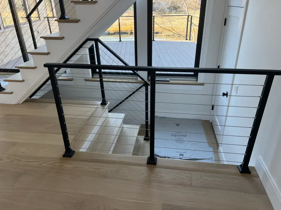 Interior cable railing on a landing with a white oak handrail