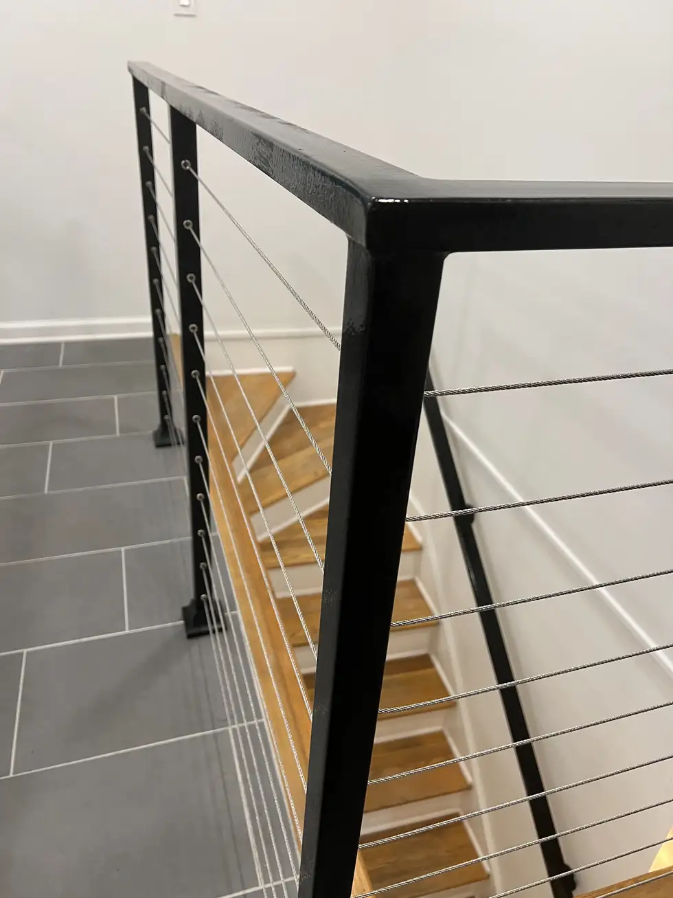 Interior cable railing with a black steel frame on stairs