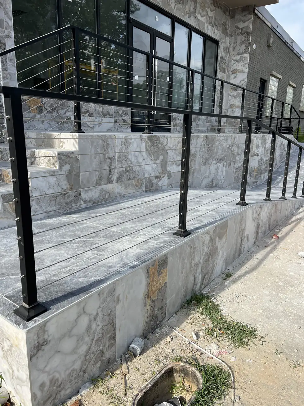 Modern stone entry stairs with a black steel cable railing