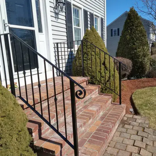 Ornamental scroll iron railing beside a brick walkway