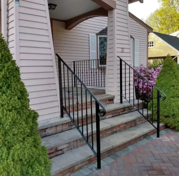 Scroll detail on an iron handrail at brick porch steps