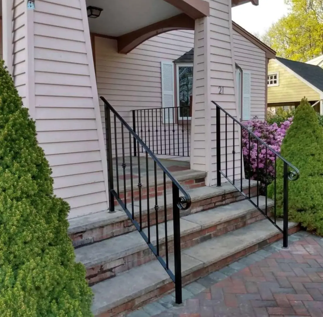 Scroll detail on an iron handrail at brick porch steps