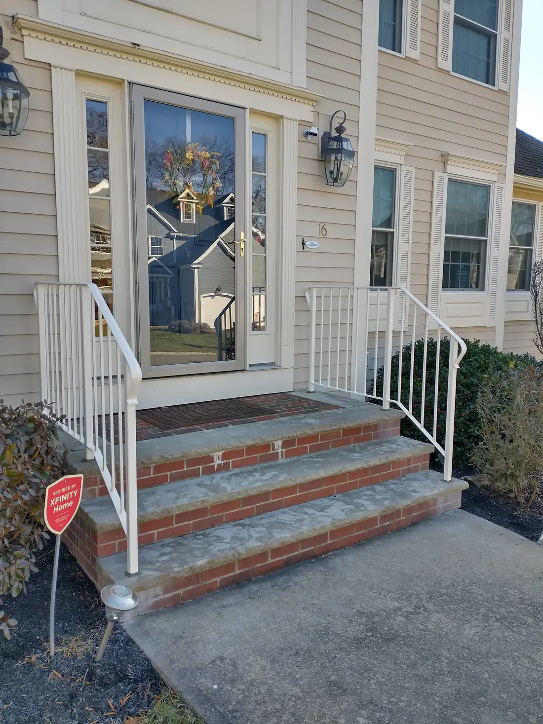 Steel handrail on brick porch steps between white columns