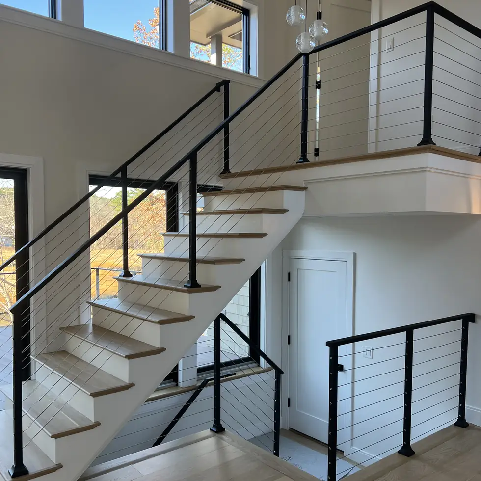 Custom designed cable stair railing with a white oak handrail inside a modern home