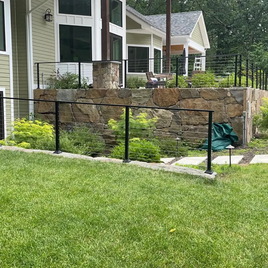 Steel fence and cable railing running along a property perimeter retaining wall
